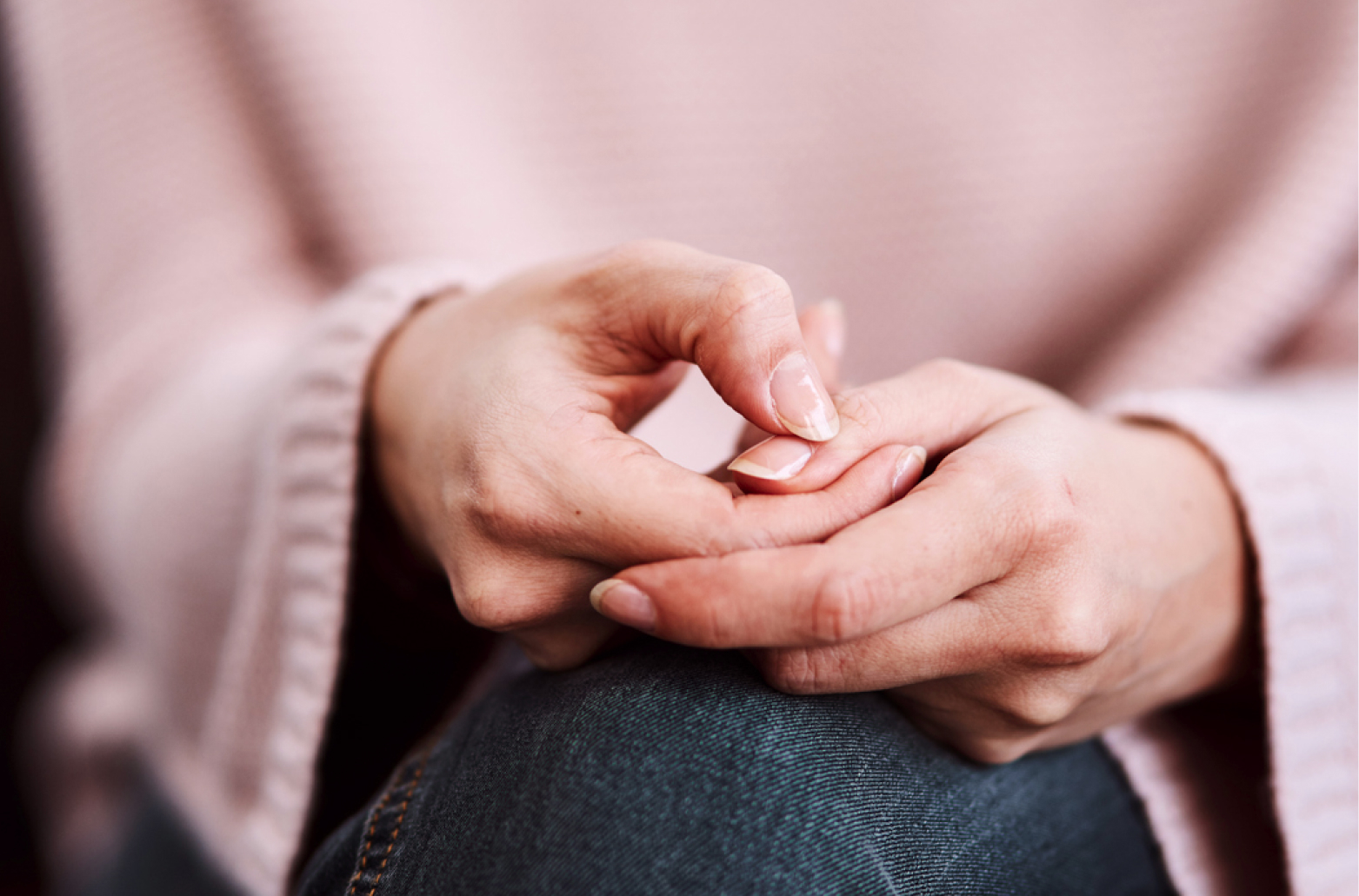 Крупный план: женщина нервно перебирает пальцами, руки сложены на колене